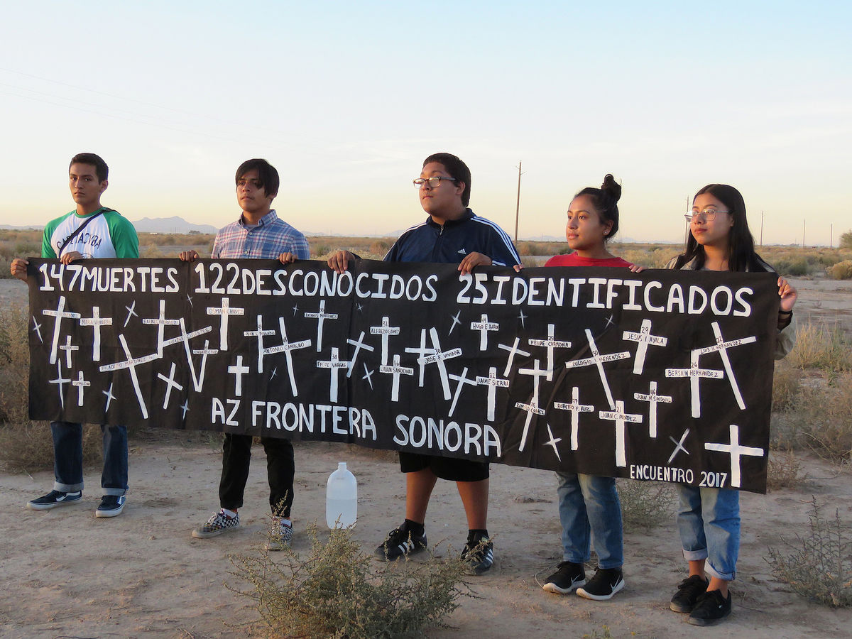 People with a sign at the US-Mexico Border
