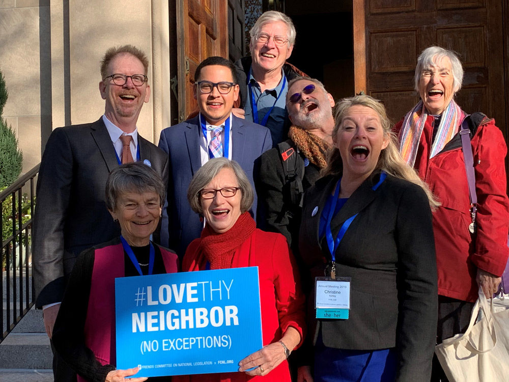 Group holding Love They Neighbor sign at annual meeting 2019