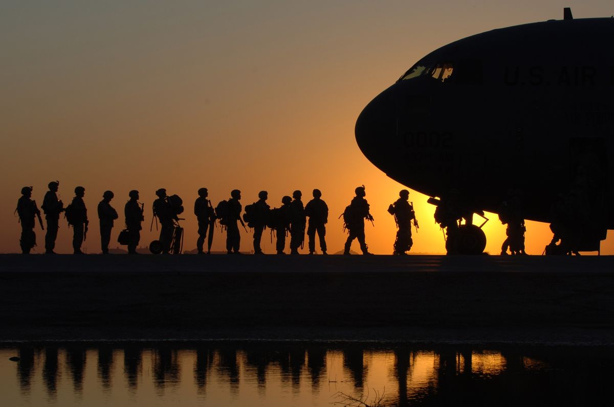 Soldiers boarding plane at sunset.