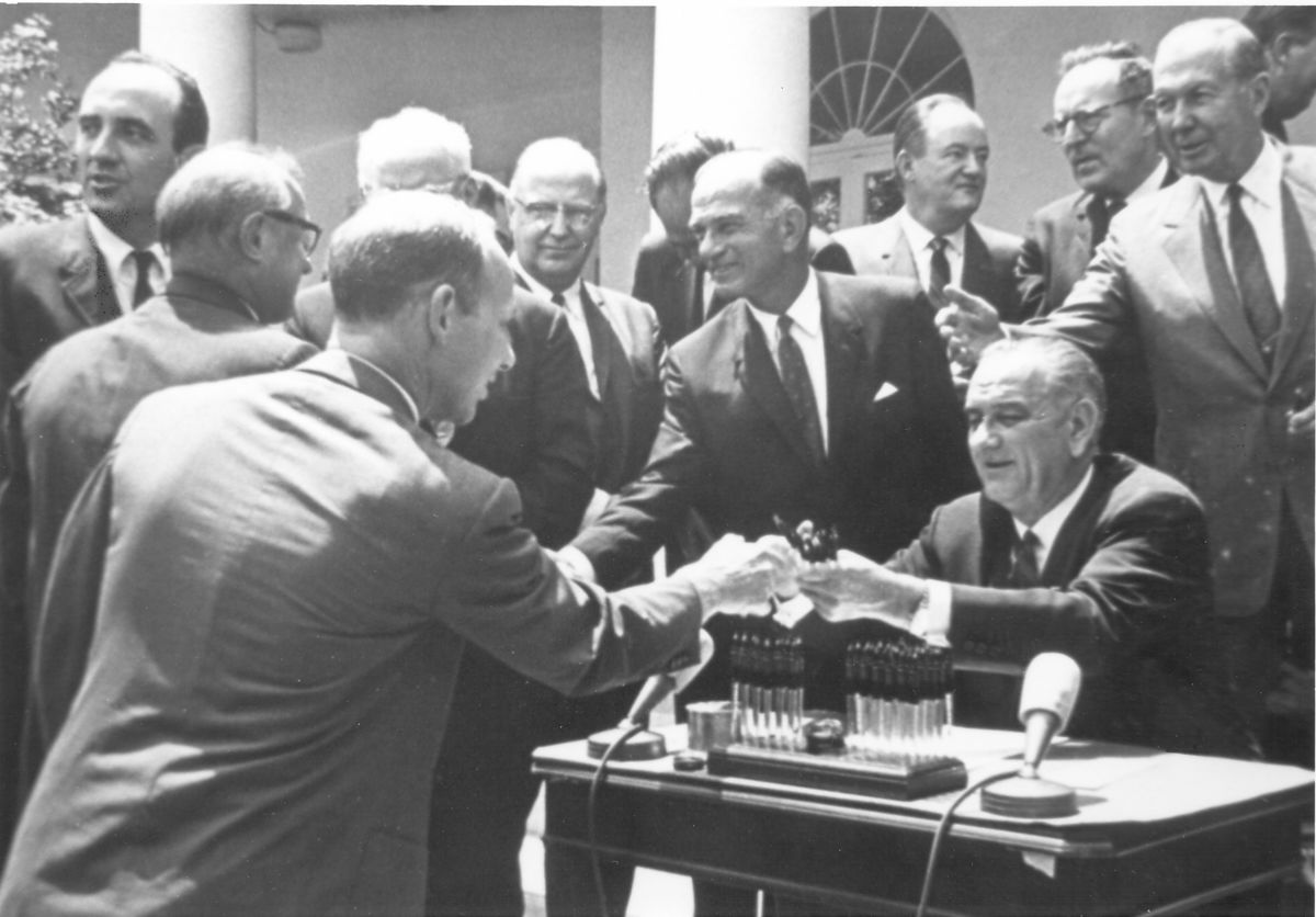 Ed Snyder receives a pen from Pres. Lyndon B. Johnson after signing the 1965 Arms Control & Disarmament Act Extension.