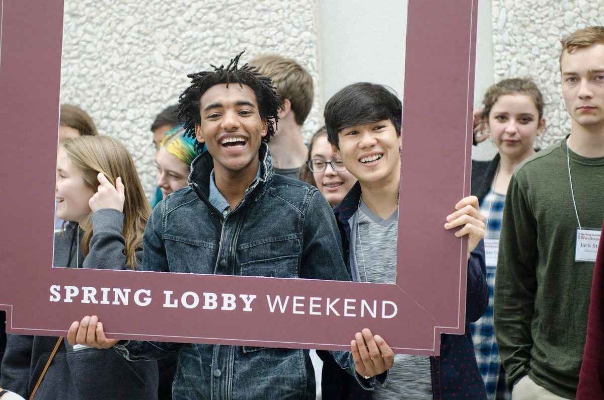 Students hold Spring Lobby Weekend sign